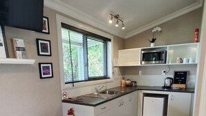 Une cuisine compacte comprenant un coin repas, un four à micro-ondes, un réfrigérateur et un petit îlot central.
