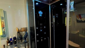 Un bagno moderno con cabina doccia in vetro, pavimento in legno e diversi articoli da toilette su uno scaffale.