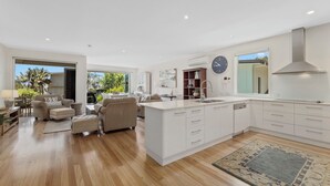 A spacious kitchen with a large island, white cabinetry, and a view of the outdoors.