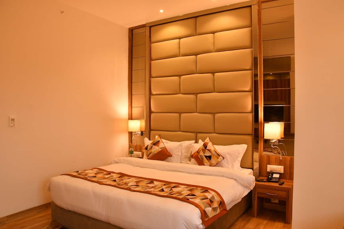 A hotel room with a large bed, bedside lamps, a nightstand, and a mirror.