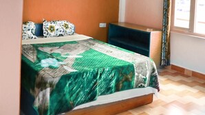 A bedroom with a bed, a ceiling fan, a window with curtains, and a wall with a built-in shelf. - Tranquil Water Guest House Pokhara (Pokhara)