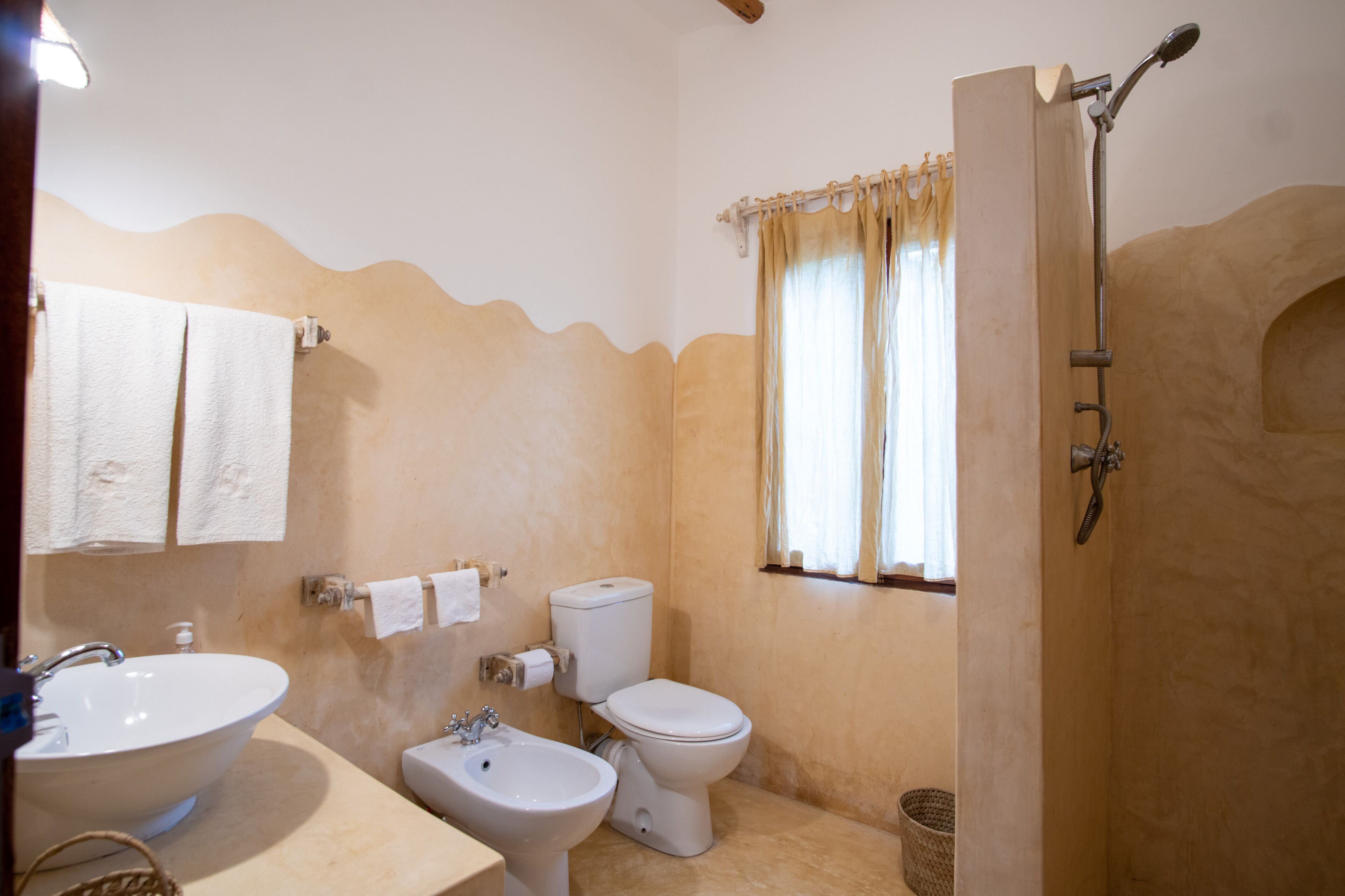A bathroom with a sink, bidet, toilet, and shower.