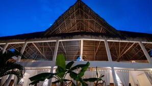A large, open-air structure with a thatched roof and white walls, featuring a central open space and multiple levels. - Rafiki Village (Watamu)