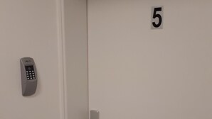 Uma porta com teclado numérico e puxador, identificada com o número 5.