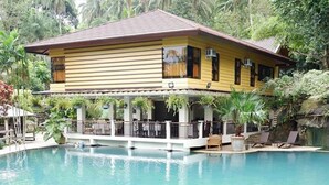 A yellow building with a pool in front.