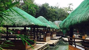 A bamboo raft with thatched roofs floating on a calm body of water, surrounded by lush greenery. - Kamayan sa Palaisdaan Hotel and Resort (Tayabas City)