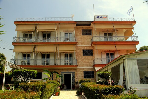 A multi-story hotel with balconies, a covered patio, and a sign indicating it is a glideroom. - Giota Rooms (Pineios)