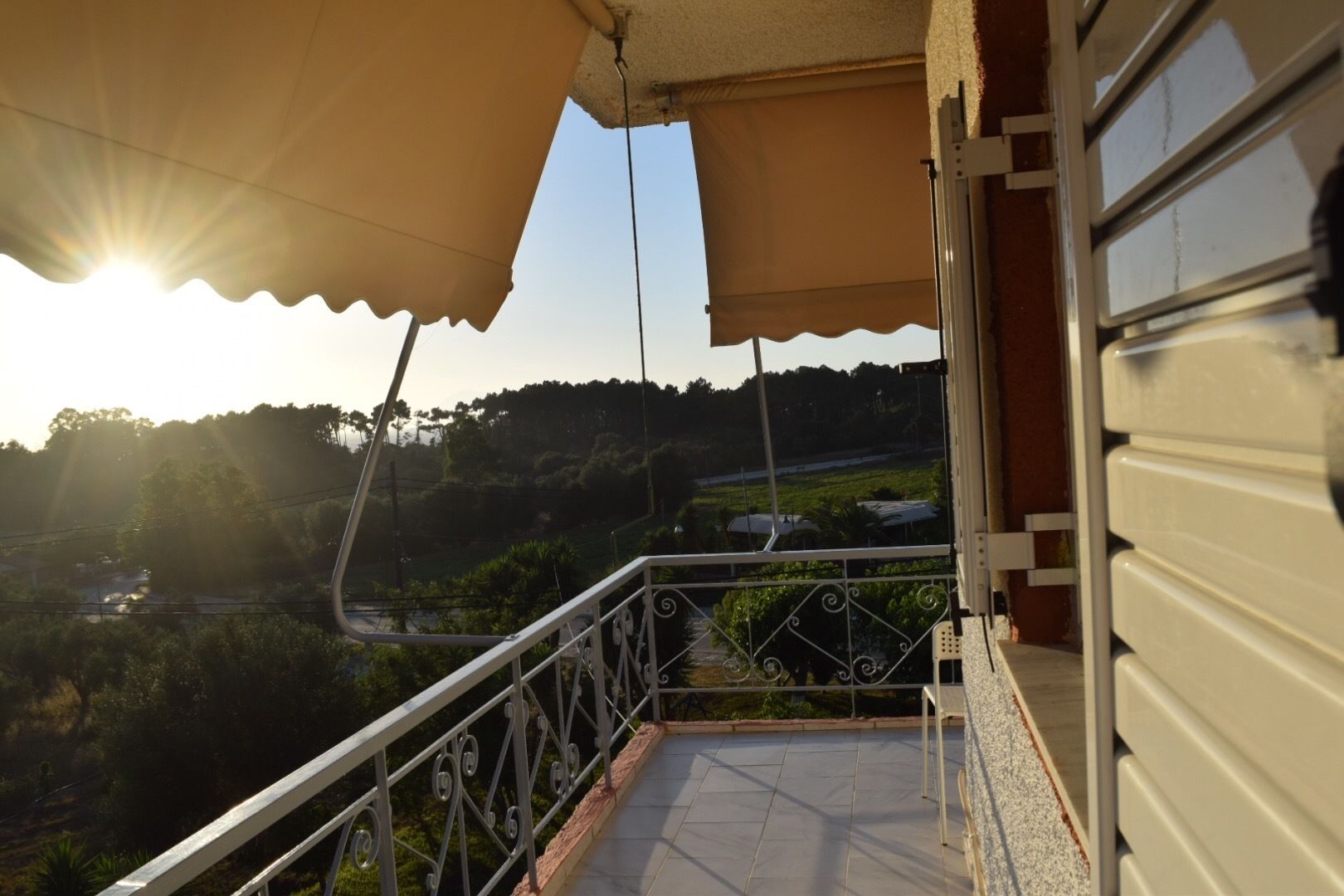 A balcony with a view of a hilly landscape and a river.