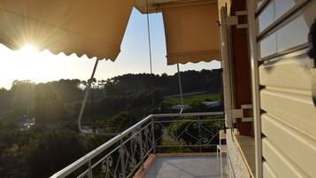 A balcony with a view of a hilly landscape and a river.