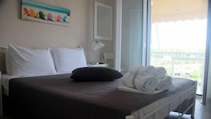 A hotel room with a bed, a painting, a lamp, and a balcony with a view. - Giota Rooms (Pineios)
