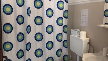 Ein Badezimmer mit Toilette, Waschbecken und einer Duschvorhang mit einem kreisförmigen Muster.