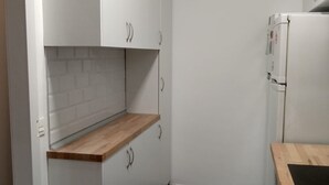 A compact kitchen with white cabinetry, a wooden countertop, and a built-in oven. - Residencial Fontanillo (Las Palmas de Gran Canaria)