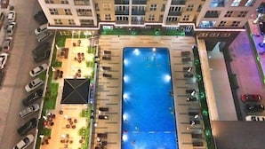An aerial view of a residential building with a swimming pool, outdoor seating, and parked cars. - Zan- Newlife Halong Apartment (Bai Chay)