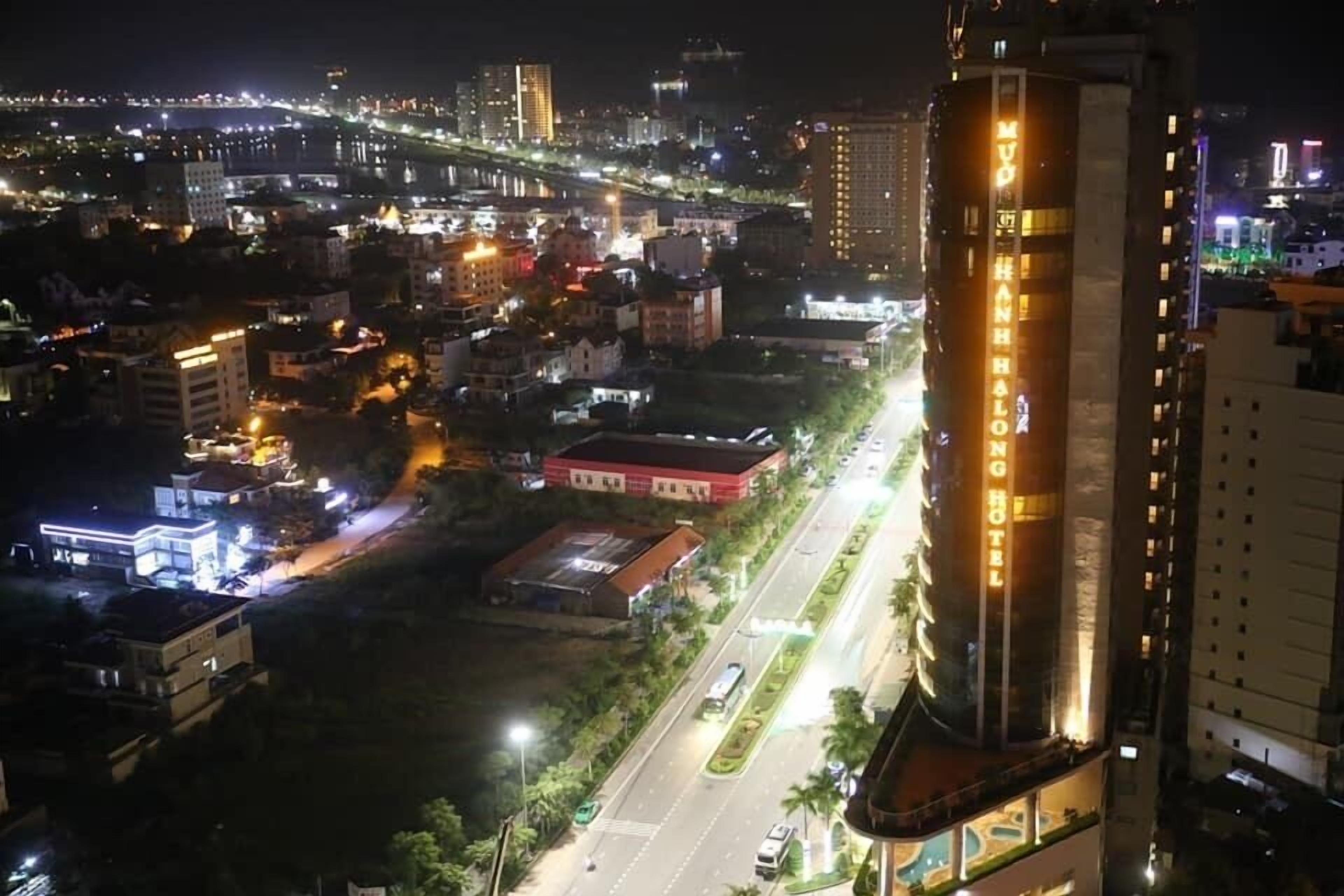 A high-rise hotel with a prominent sign, a well-lit street, and surrounding buildings.
