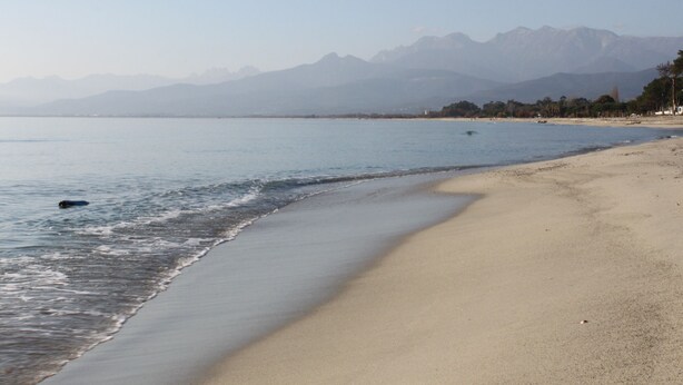 Ein Strand mit freiem Blick auf Berge im Hintergrund.