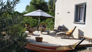 Eine Terrasse im Freien mit einer Hängematte, Korbstühlen und einem Tisch.