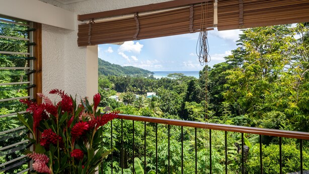 Ein Balkon mit Blick auf üppiges Grün und ferne Hügel.