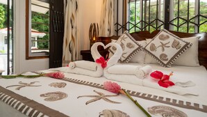 Ein ordentlich gemachteres Bett mit Handtüchern, die zu Herzen geformt sind, einer rosa Blume und Meeressternen-Muster auf der Bettdecke.