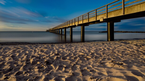 A long pier extending into calm waters, with a sandy beach in the foreground. - High quality and fully equipped apartment only 3km from the Baltic Sea (Stakendorf)