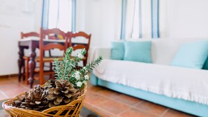Una sala de estar acogedora con un sofá, una mesa de comedor y una cesta de mimbre con piñas.