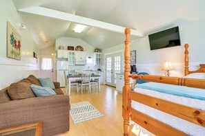 A cozy bedroom with a wooden bed, a sofa, and a kitchen in the background.
