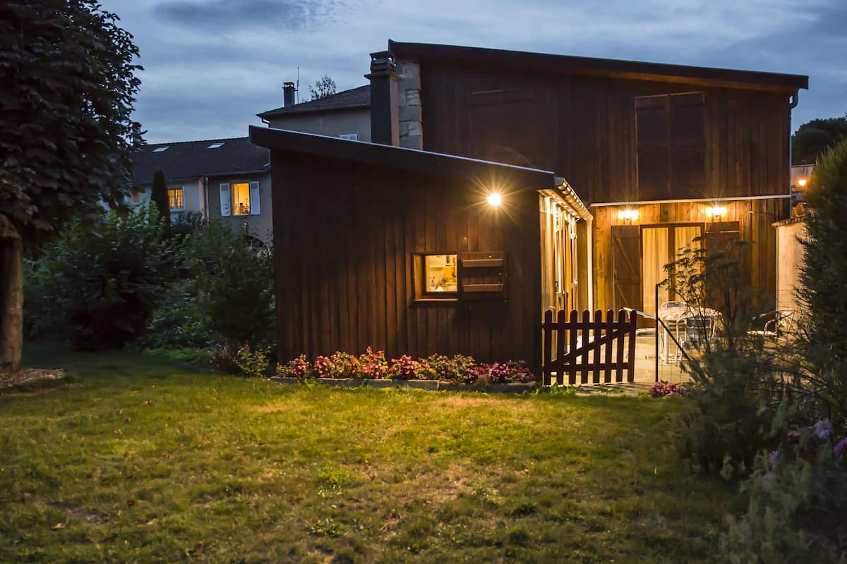 A two-story wooden house with a visible garage door and a small porch area.