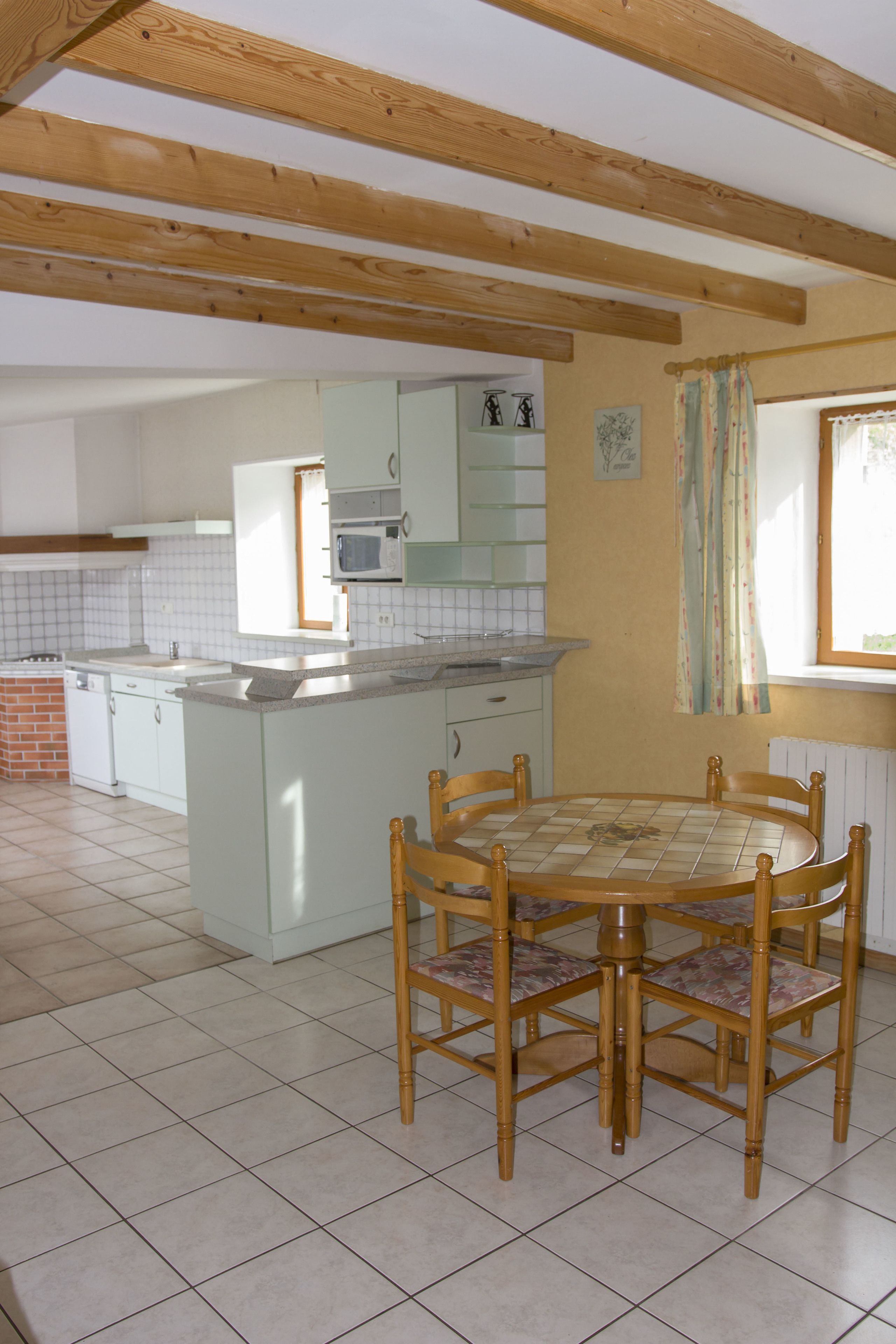 Een keuken met witte kastjes, een betegelde achterwand en een houten plafond.