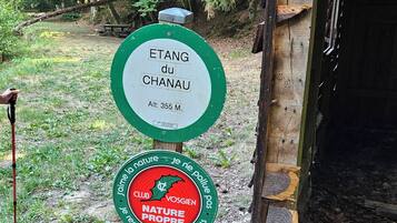 Um sinalizador com duas placas, uma indicando a altitude de Etang du Chanau e outra promovendo a proteção da natureza.