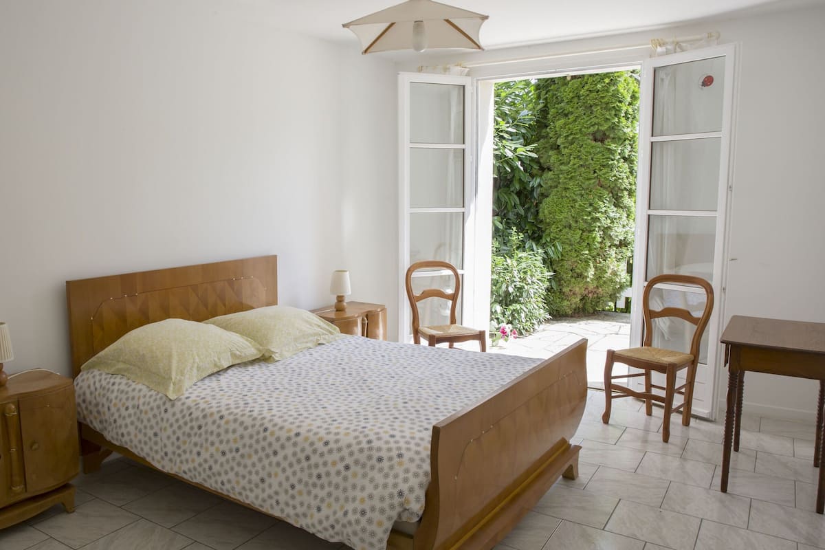 A bedroom with a wooden bed, two bedside tables, a nightstand, and a chair.
