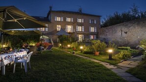 Um jardim bem cuidado com área de refeições, iluminação externa e muro de pedra.
