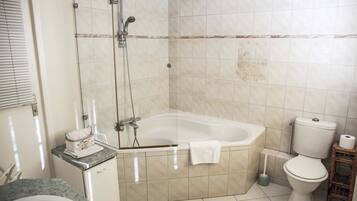 Ein Badezimmer mit Badewanne, Toilette und Duschbereich.