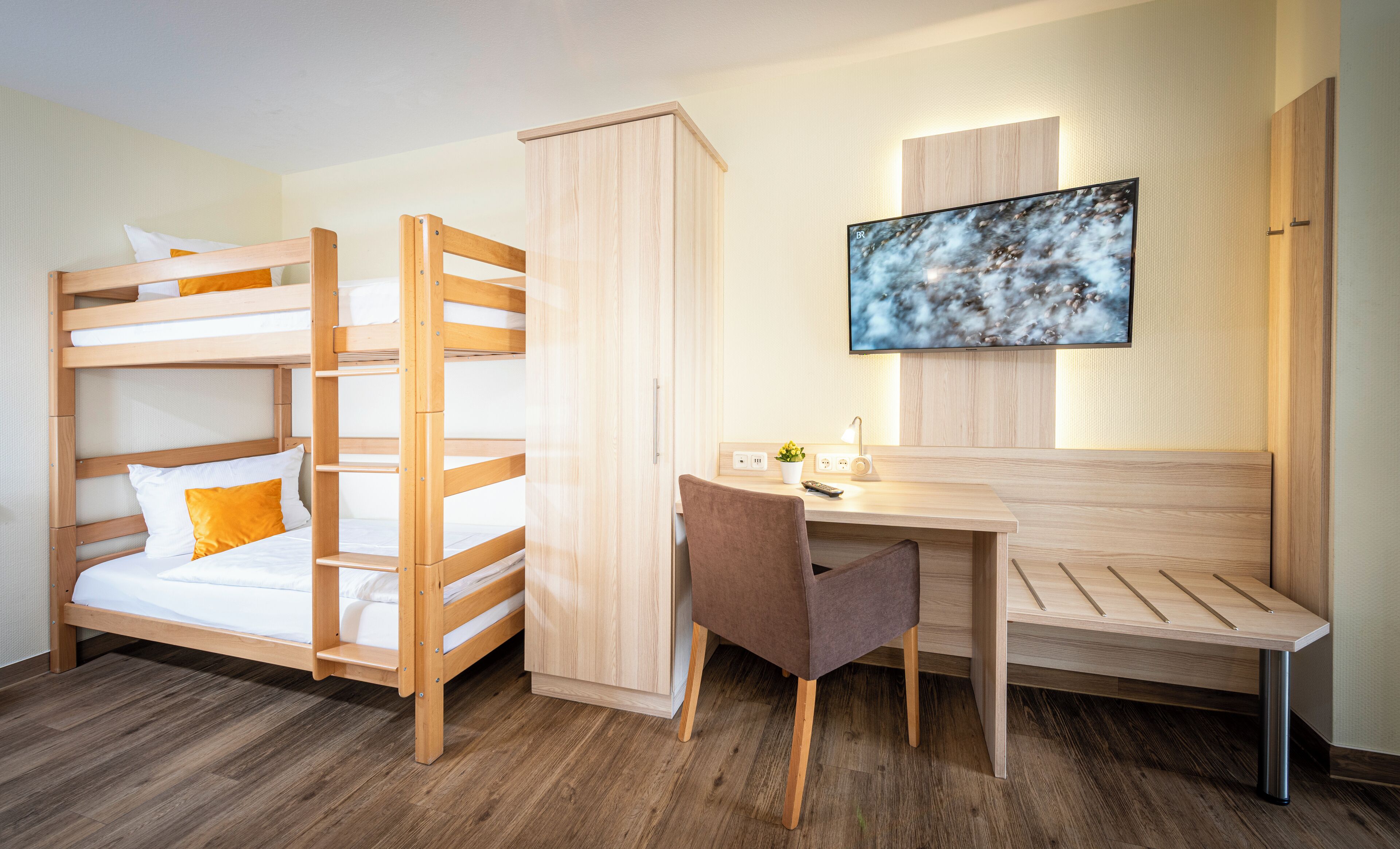 A bunk bed room with a desk and chair, a television, and a cabinet.