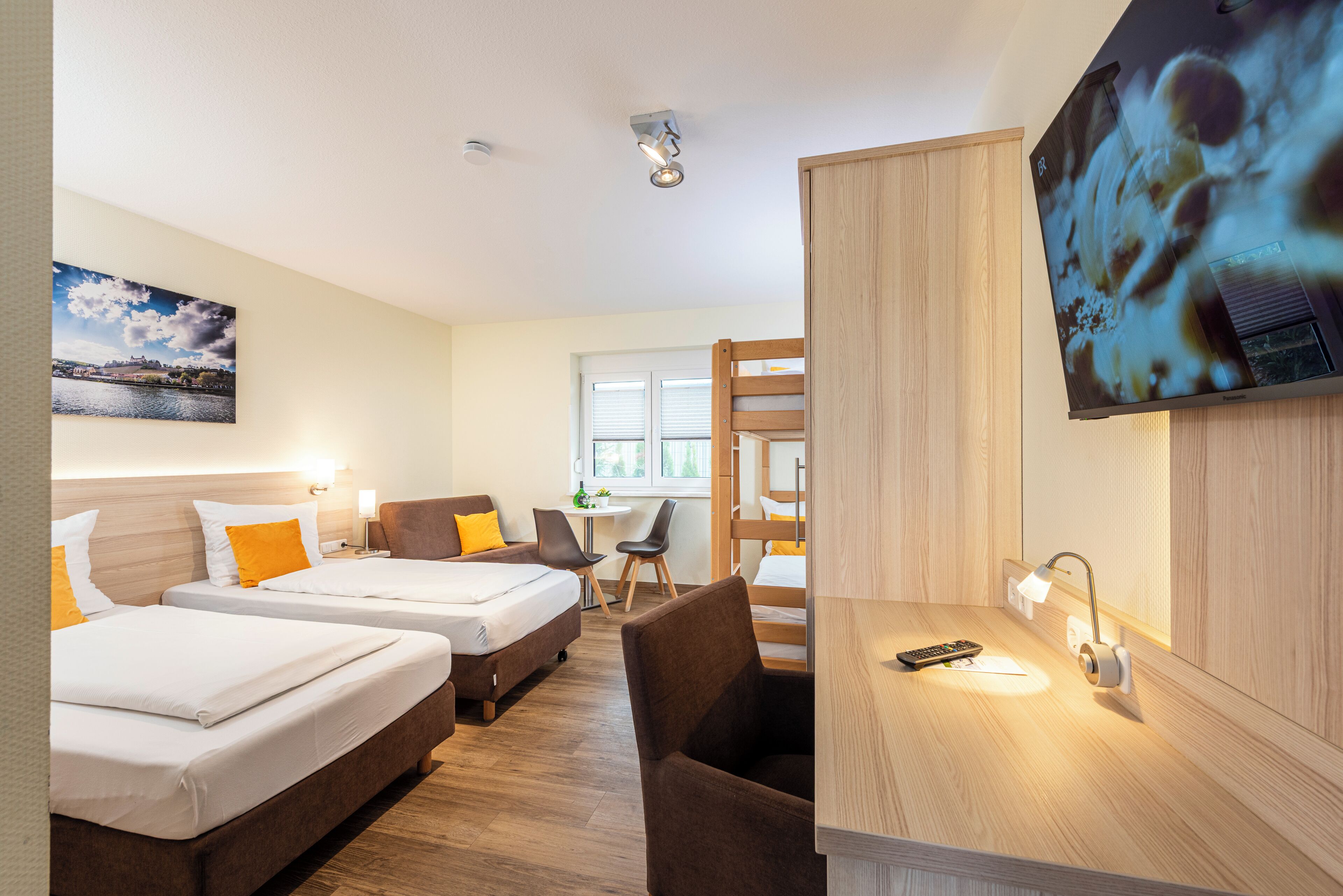 Une chambre d’hôtel avec deux lits, un bureau, une chaise, une télévision et une fenêtre.