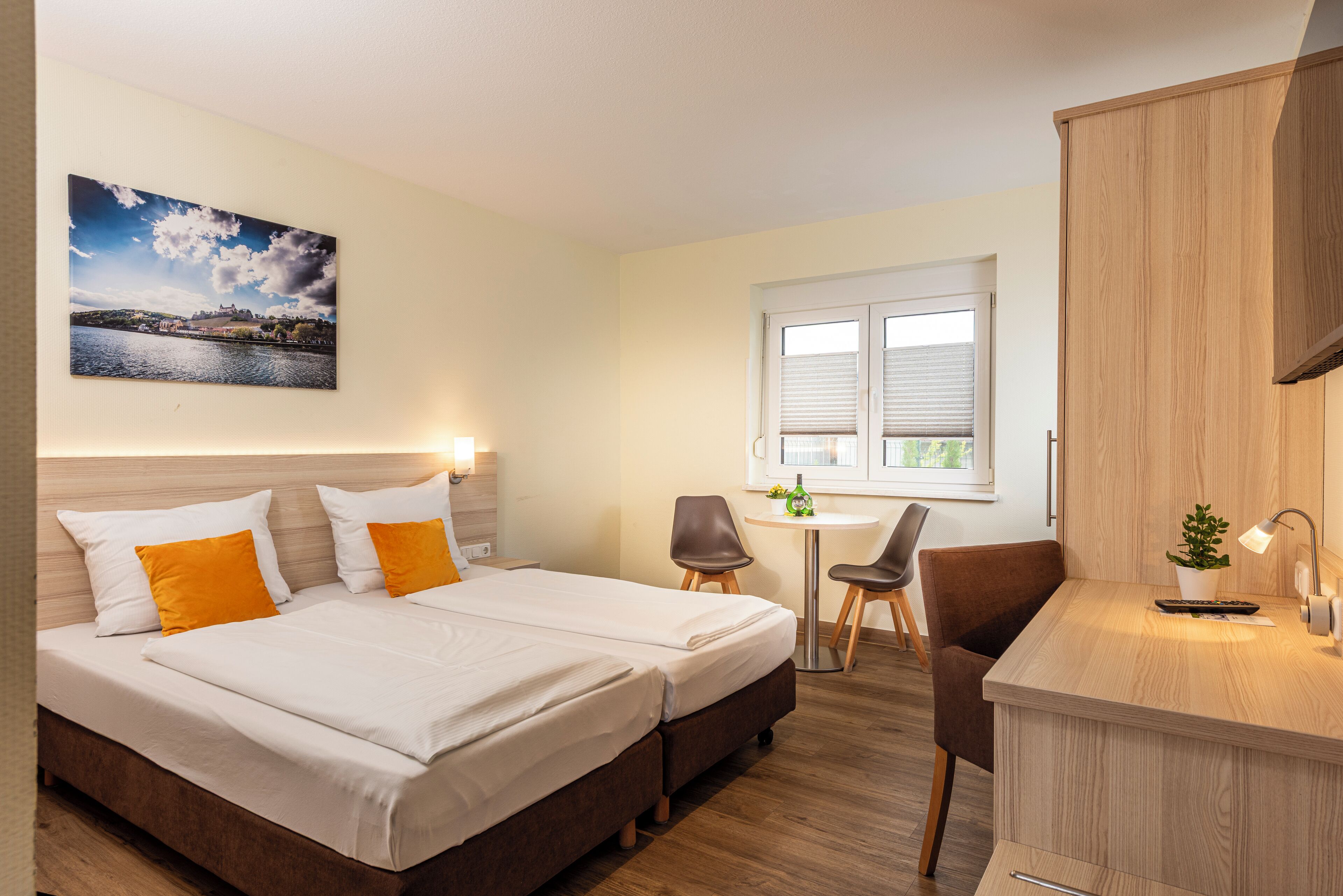 Habitación de hotel con cama, escritorio, silla y ventana.