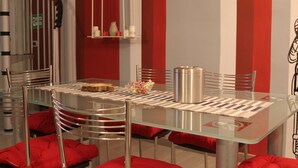 A modern dining area with a glass table, metal chairs, and red cushions. - Sesta Strada guesthouse (Civitavecchia)
