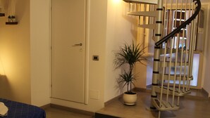 A bedroom with a bed, a potted plant, a staircase, and a door. - Sesta Strada guesthouse (Civitavecchia)