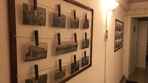 A hallway with a wall-mounted photo display using clothespins. - Sesta Strada guesthouse (Civitavecchia)