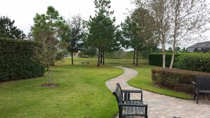 Un sendero pavimentado que atraviesa un parque con bancos y árboles.