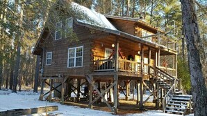 A wooden cabin with a balcony, surrounded by trees and snow. - The Log Cabin on the Canoochee River (Evans County)