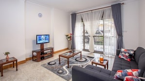 Una sala de estar con sofá, mesa de centro, televisor y vistas al exterior.