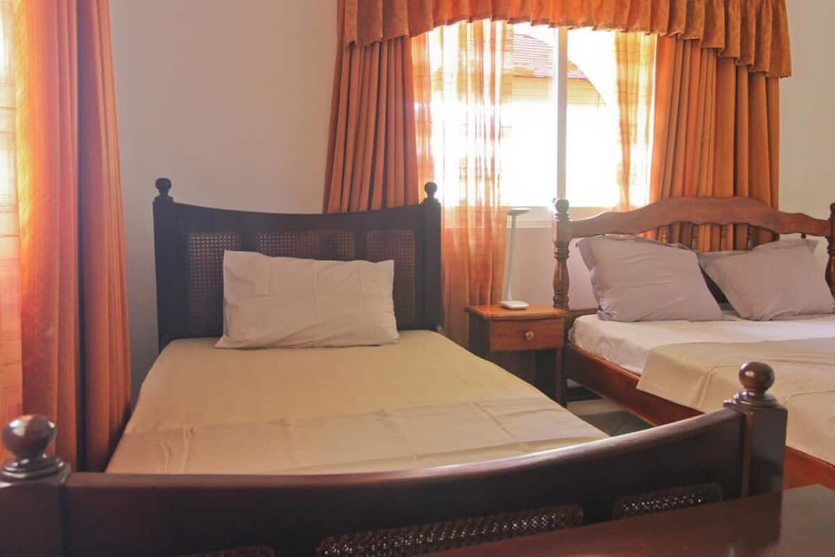 A double bed with a wooden headboard, a bedside table, and a window with curtains.