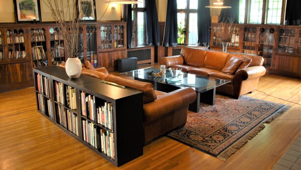 A spacious living room with a leather sofa, a coffee table, and a bookshelf filled with books. - Architect's 3 Story Brownstone 4B4B Loring Heights (Minneapolis)