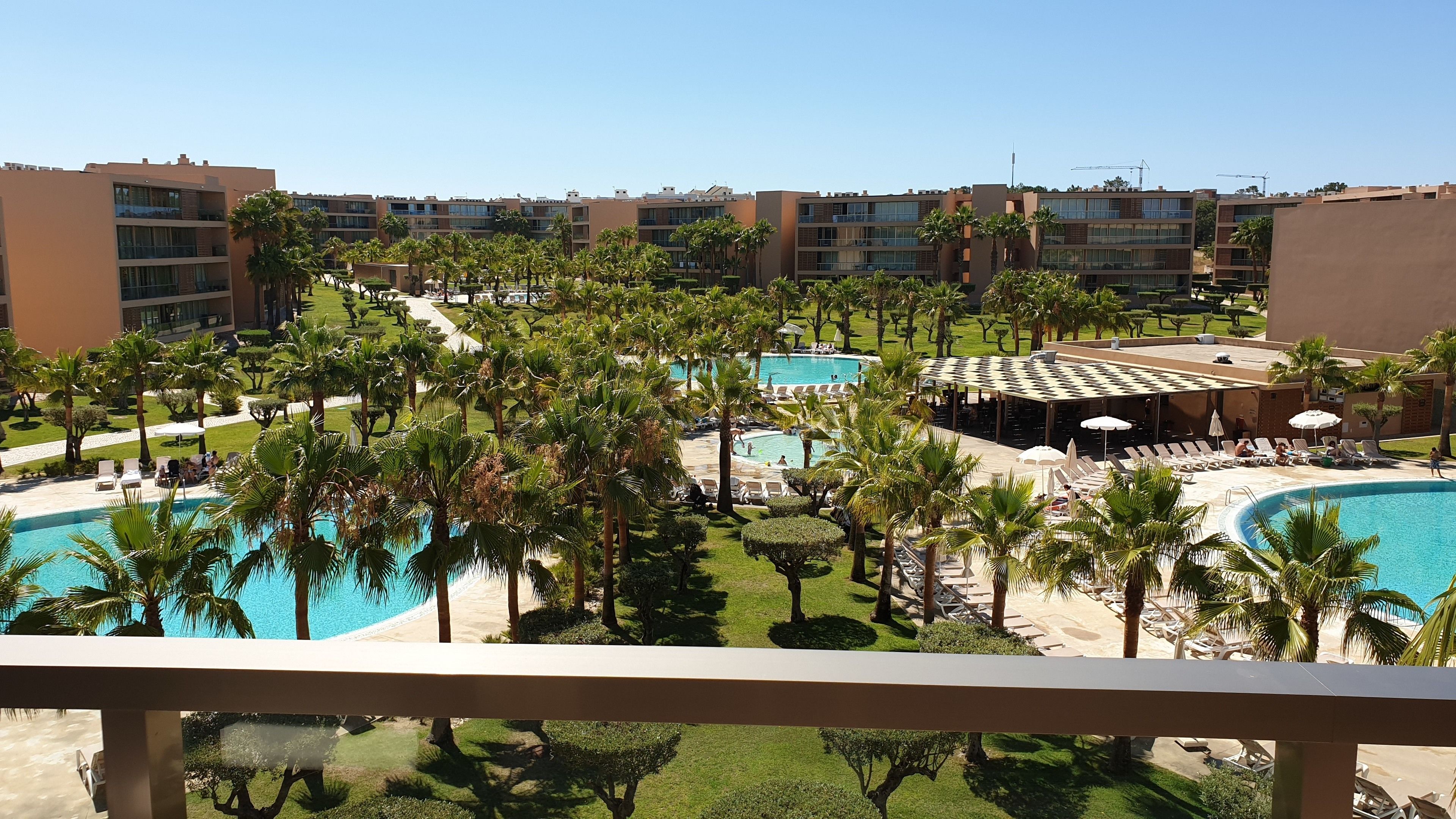 Un complexe hôtelier doté de plusieurs piscines, de palmiers et d’espaces de détente.