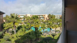 A hotel with a pool surrounded by palm trees and a view of other buildings in the background. - Salgados Beach Vila das Lagoas (Albufeira)