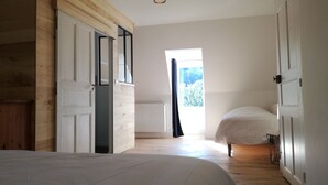 A bedroom with a wooden door, a window with a view of greenery, and a bed. - Gite le Marquès in Aubrac with spa (Saint-Chély-d'Aubrac)