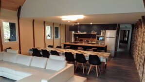 A modern kitchen with a dining area, a white sofa, and a long table. - Gite le Marquès in Aubrac with spa (Saint-Chély-d'Aubrac)
