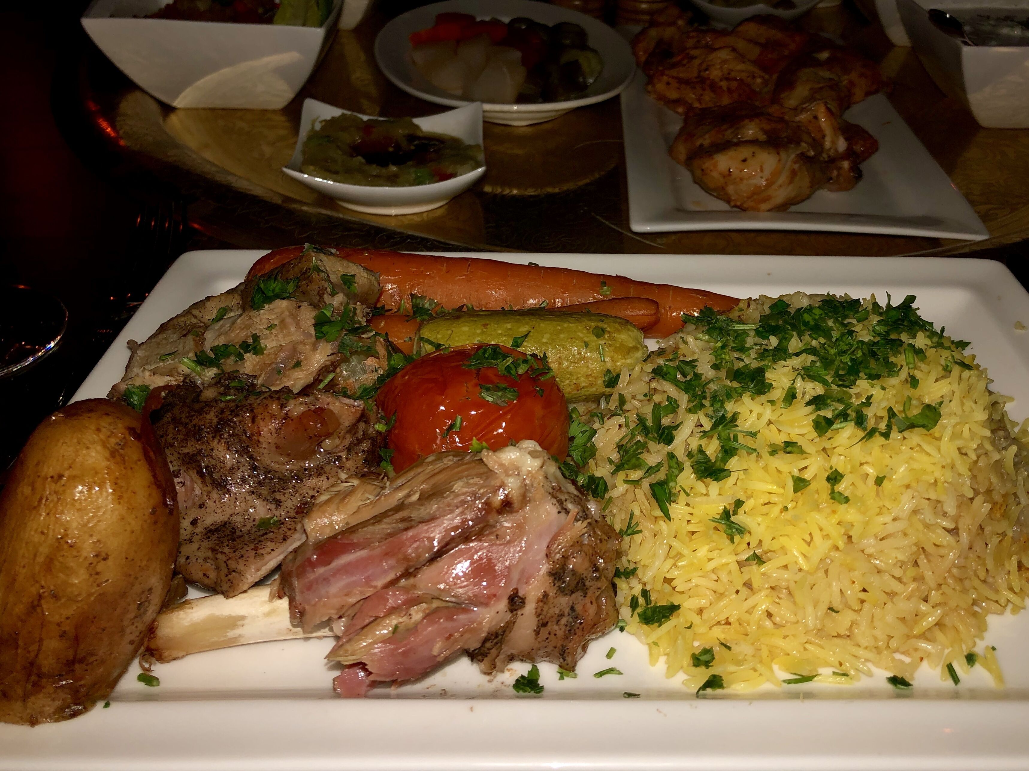 A plate of food including roasted meat, vegetables, and rice.