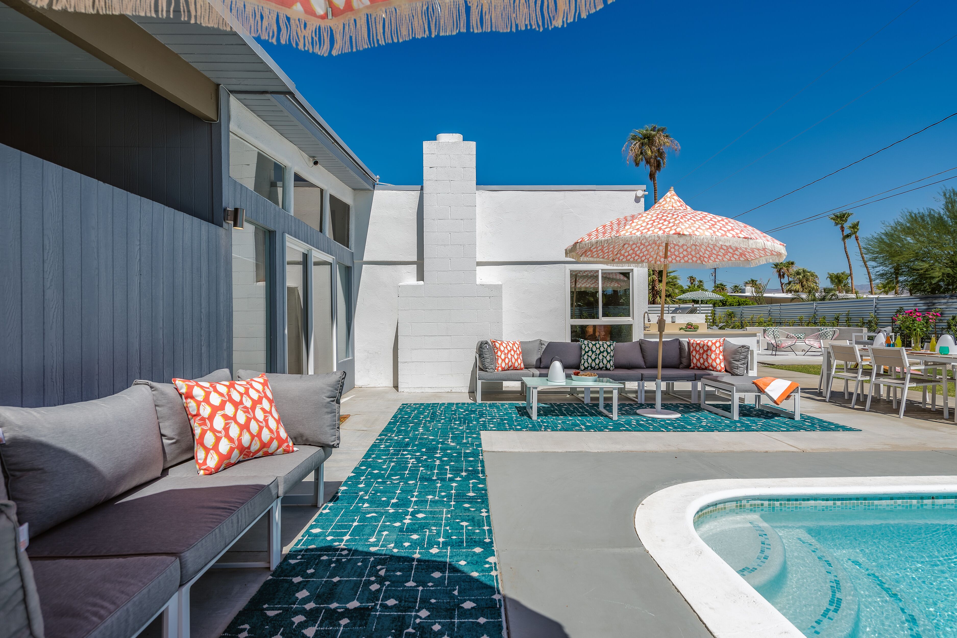 A poolside area with a pool, outdoor seating, and a patio umbrella.