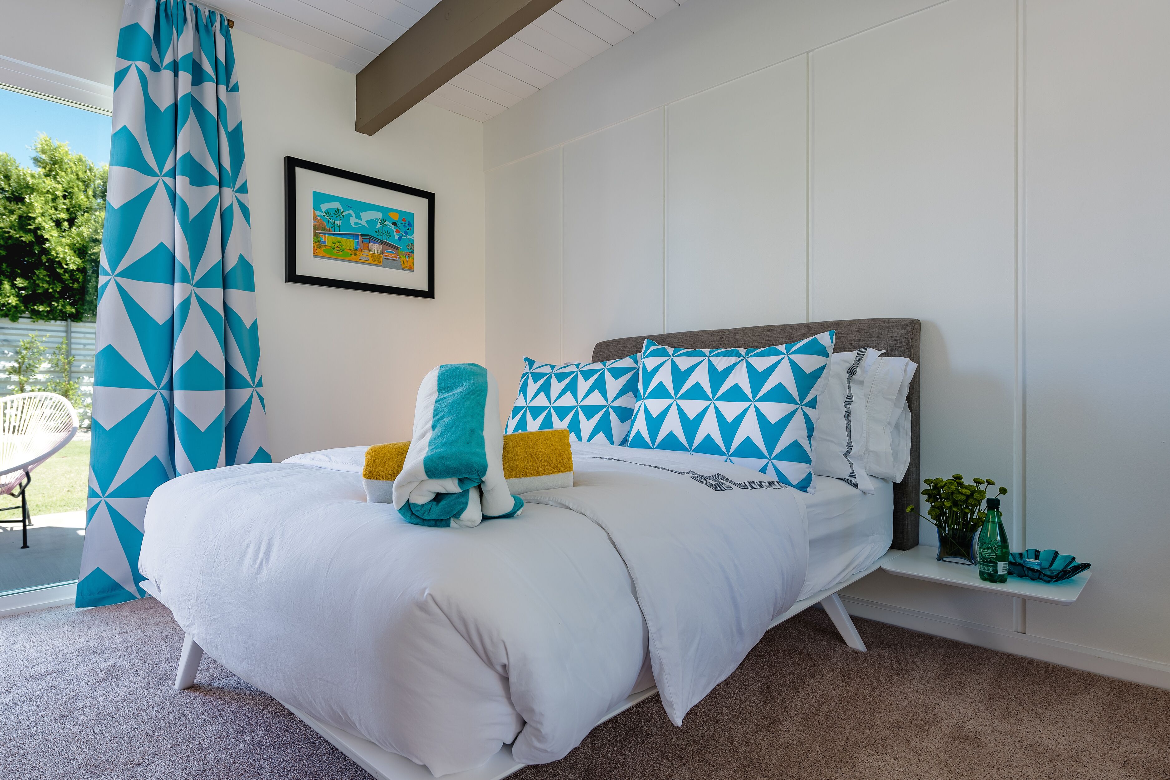 A bedroom with a bed, a nightstand, a chair, and a window with curtains.