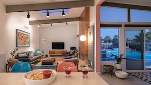Un salón moderno con un televisor grande, asientos cómodos y vistas a una piscina.